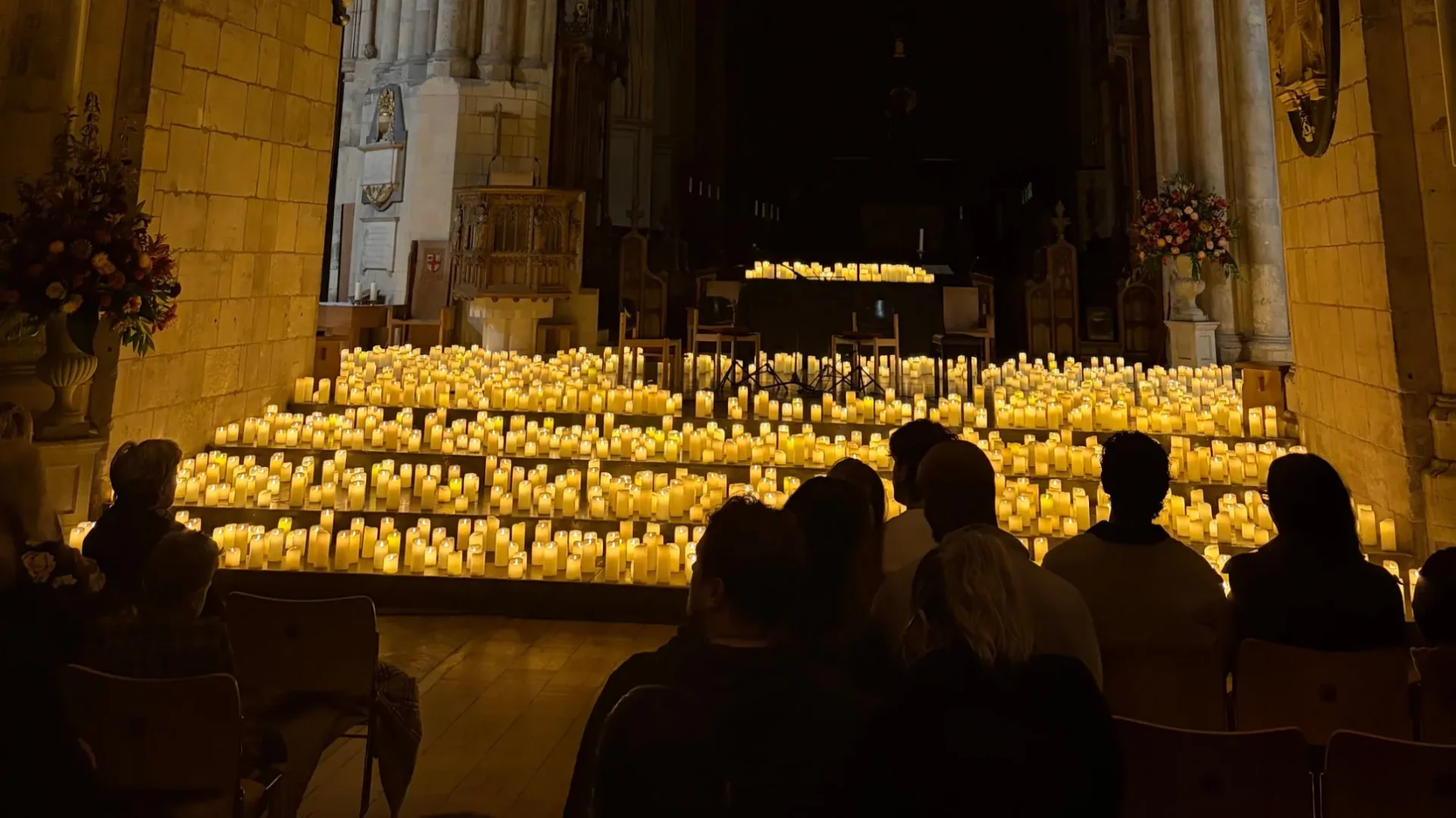 The audience at Candlelight: Disney Love Songs, seated on one level in Southwark Cathedral, with heads in front partly blocking the candlelit stage