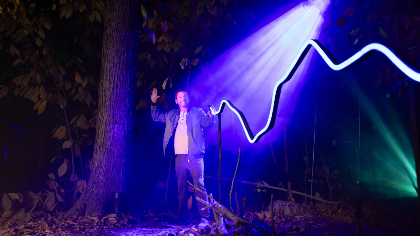A visitor raising a wand towards a purple beam of light during the wand duel